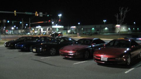 1993 Ford Probe - A group of Ford Probes are parked in a lot at night, with a gas station and store in the background.