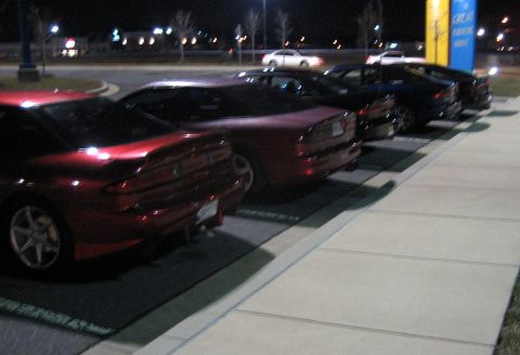 1993 Ford Probe - Several cars are parked in a lot at night, with a red coupe in the foreground.