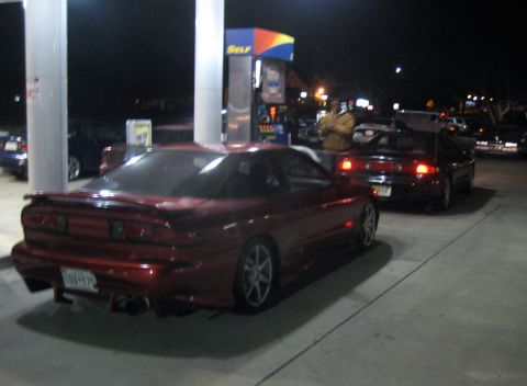 1993 Ford Probe - Two cars are at a gas station at night, with one red coupe in the foreground.