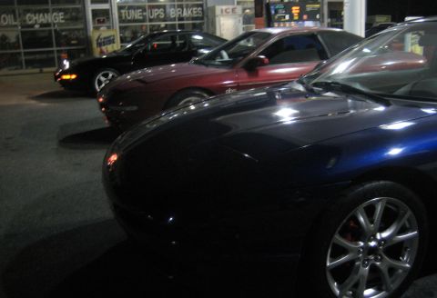 1993 Ford Probe - Three Ford Probes are lined up in front of a service station at night.