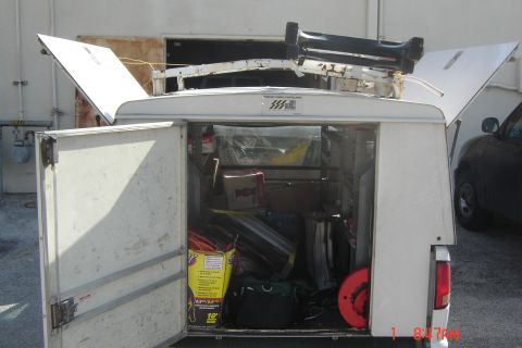 2006 Honda CBR-RR - Rear view of a white utility truck bed loaded with various tools and equipment, with doors ajar.