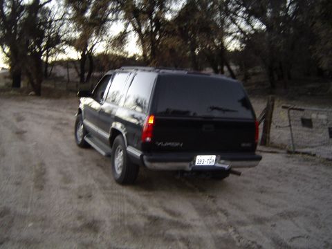 1989 Ford Bronco - A black SUV is parked on a dirt road during the day, with trees visible in the background.