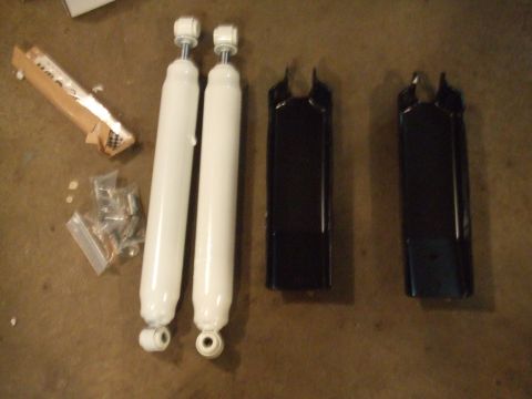1996 Ford Bronco - New shock absorbers and mounting hardware are laid out on the floor, ready for installation.