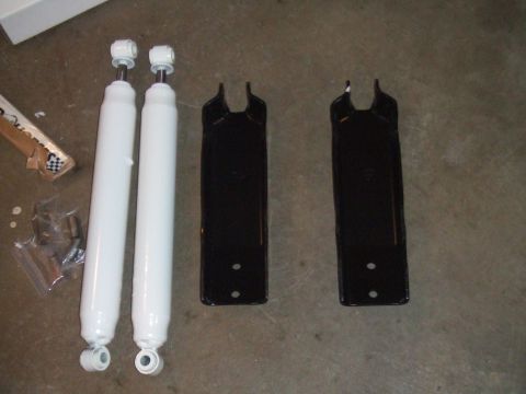 1996 Ford Bronco - Vehicle parts, including shock absorbers and mounting brackets, are laid out on a concrete surface.