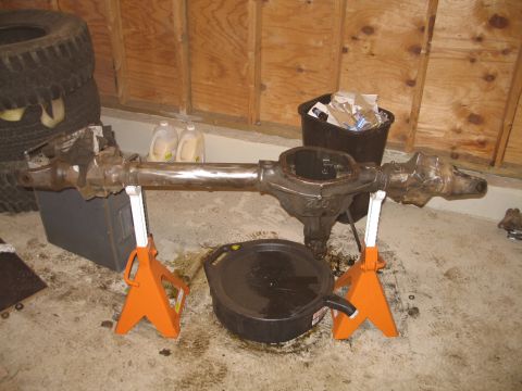 1995 Ford Bronco - A differential axle assembly is shown supported by orange jack stands in a garage setting.