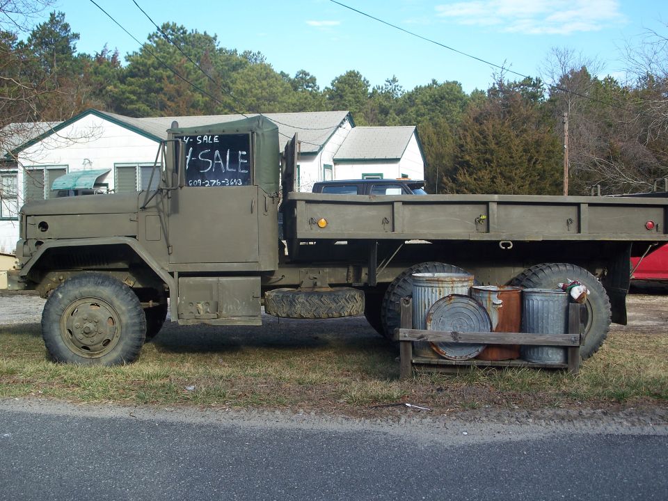 Olive drab military truck side view with "For Sale" sign
