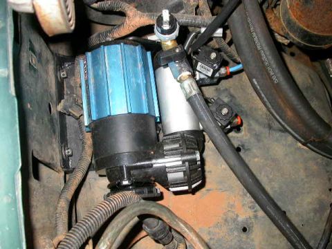 1990 Ford Bronco - Close-up of an aftermarket on-board air compressor system installed in a vehicle's engine compartment.