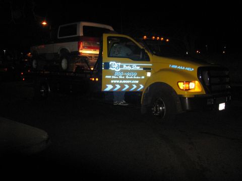 1989 Ford Bronco - A white and brown 1987 Ford Bronco is loaded onto a yellow tow truck at night.