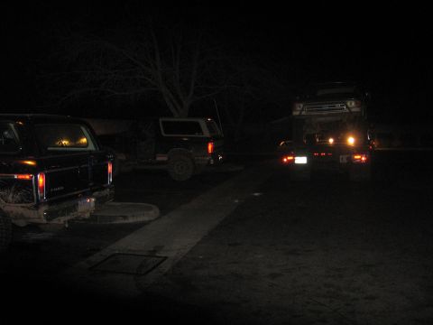 1989 Ford Bronco - Three Ford Broncos are parked outside at night, with one loaded onto a trailer.