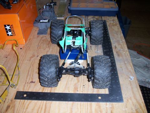 1996 Ford Bronco - RC monster truck chassis assembly on a workbench with tools and parts.