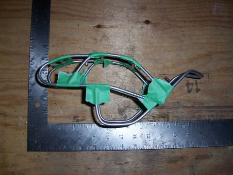 1996 Ford Bronco - Metal tubing part secured with green tape, placed next to a ruler on a wooden workbench.