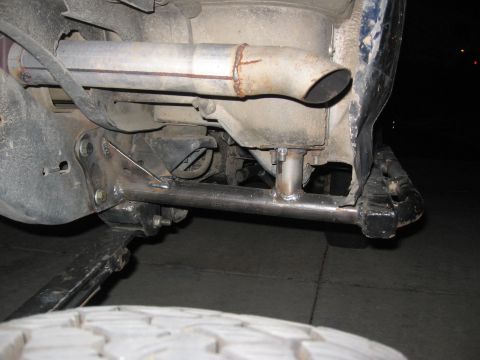 1994 Ford Bronco - Undercarriage view of a vehicle's exhaust system and suspension components, with a tire visible in the foreground.