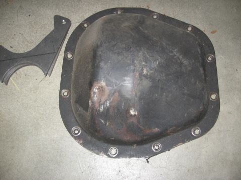 1994 Ford Bronco - A black differential cover and a metal bracket are shown on a concrete surface.