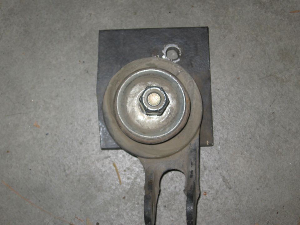 Steel bracket plate with bolted rubber bushing mount and forked arm on concrete