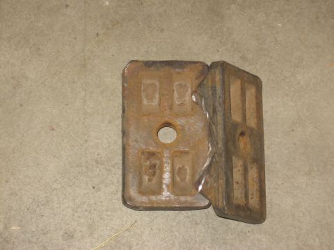 1994 Ford Bronco - Two rusty metal plates with a central hole and recessed square patterns are shown on a concrete surface.