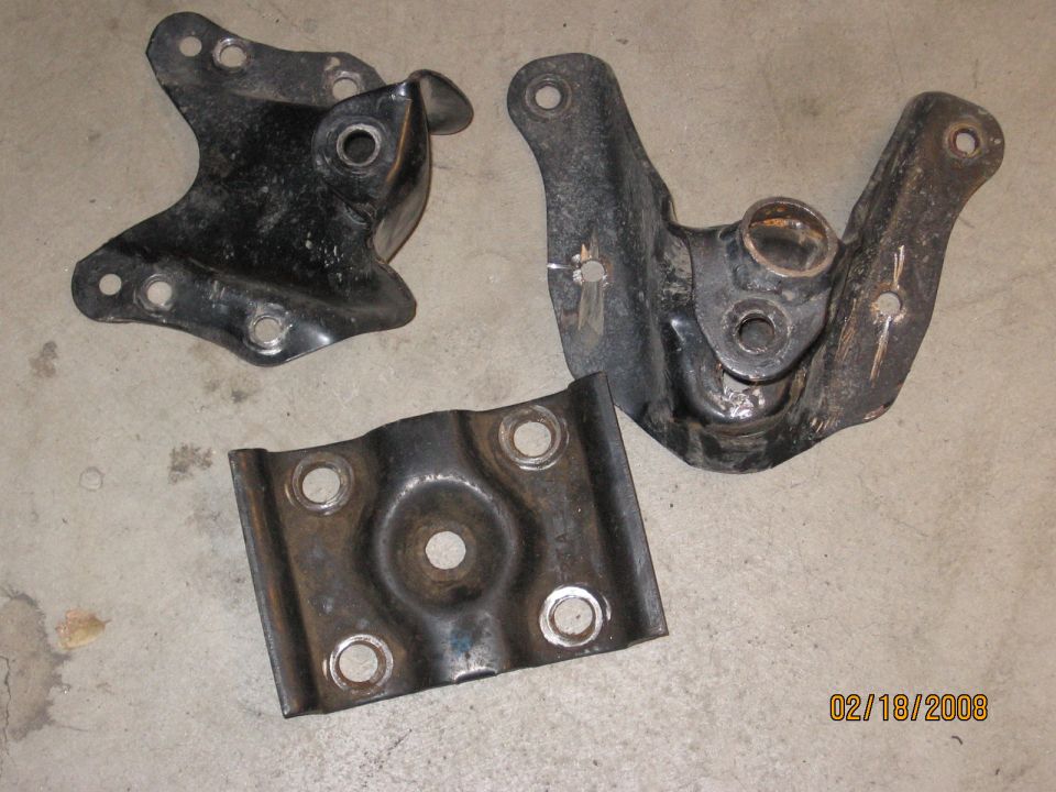 Three black steel spring perches or mounts on a concrete floor