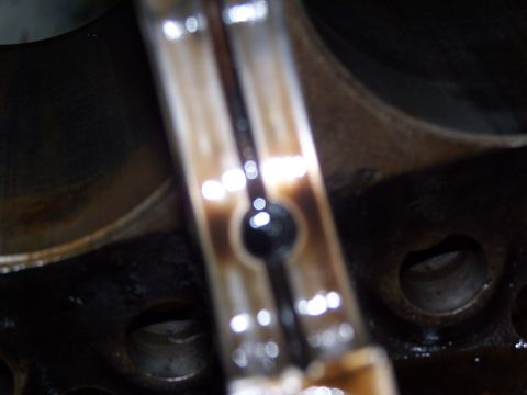 1974 Ford F-100 - A close-up view of a used engine connecting rod, showing signs of wear and oil accumulation.