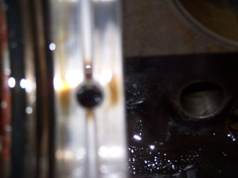 1974 Ford F-100 - A close-up view of an engine component, possibly a bearing or valve, with a dark, textured surface and bright, out-of-focus lights in the b…