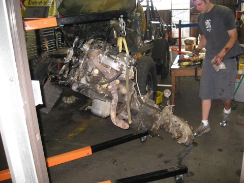 1994 Jeep YJ - Mechanic removes engine and transmission from a Jeep using an engine hoist in a garage.