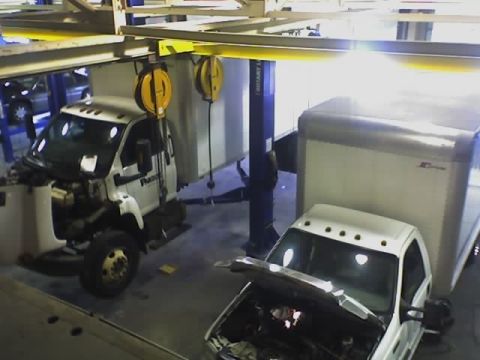 1992 Ford Bronco - Two white trucks are parked in a garage, with one having its hood open for service.