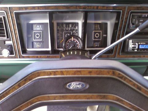 1978 Ford Bronco - The interior of a vehicle shows the dashboard with gauges, a steering wheel, and a radio.