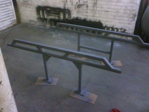 1990 Ford Bronco - Two rock sliders are mounted on stands in a workshop setting.