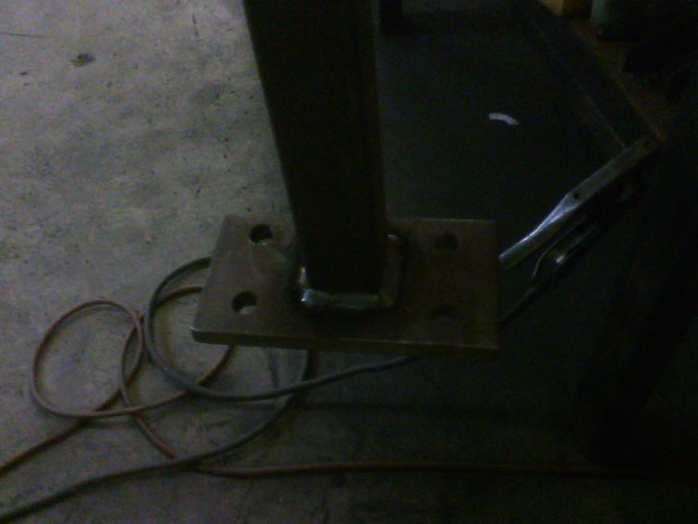 metal bracket with holes bolted to a vertical post, welding equipment nearby