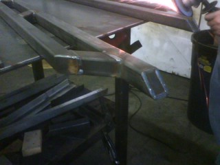 1990 Ford Bronco - Custom rock sliders are being welded and ground in a workshop, with the Supermotors logo in the corner.