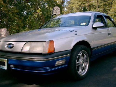 1986 Ford Taurus - This 1986 Ford Taurus is shown from a 3/4 front angle, a two-tone silver and blue paint scheme.