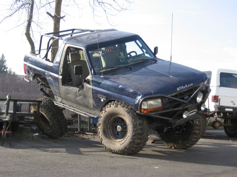 1994 Ford Bronco - Modified blue Ford Bronco with large tires and a custom bumper is parked next to a white vehicle.