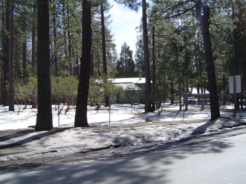 1989 Ford Bronco - A house sits in a snowy forest clearing, surrounded by tall pine trees.