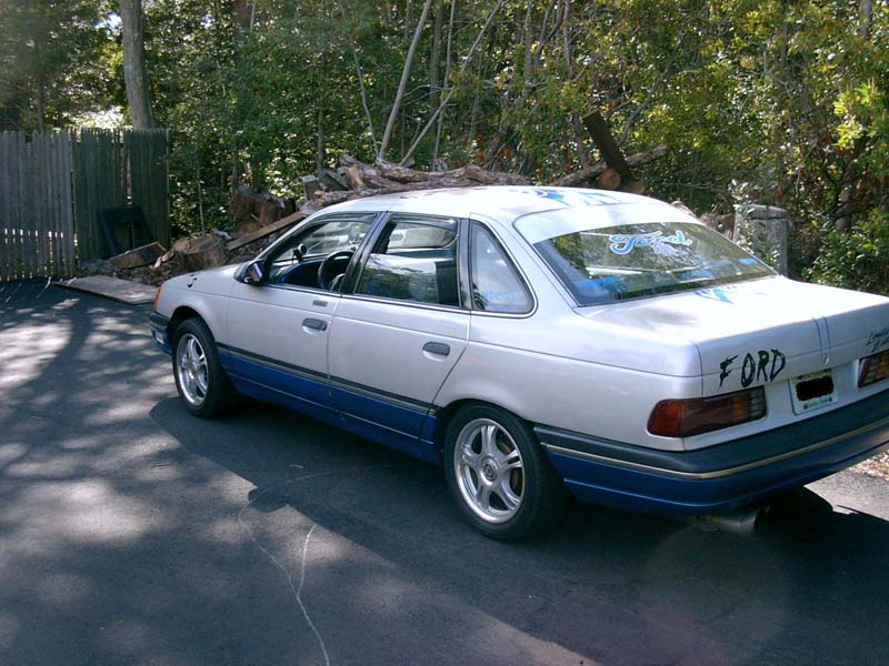 White and blue Ford Taurus sedan, rear three-quarter view with FORD written on the trunk lid