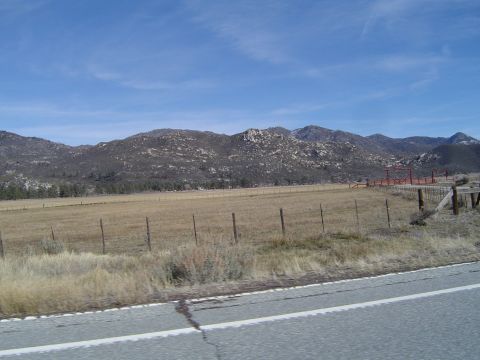 1989 Ford Bronco - A wide view of a mountainous landscape with a dry field and fence in the foreground.