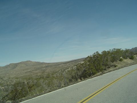 1989 Ford Bronco - A road winds through a dry, scrub-covered landscape with mountains in the distance.