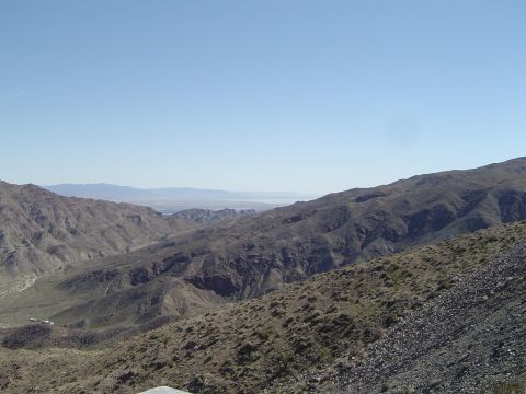 1989 Ford Bronco - A vast mountain range stretches out under a clear blue sky, with a valley visible in the distance.