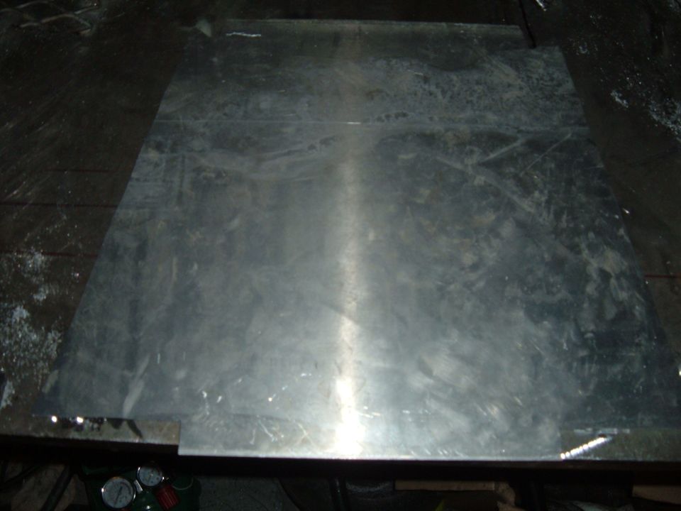 Cut sheet-metal blank on a steel workbench with welding gauges below