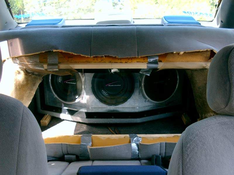 car interior with three subwoofers installed in the back, some upholstery is torn