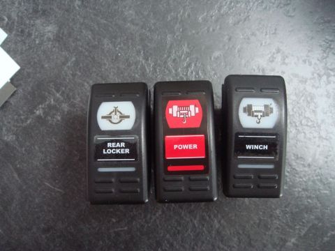 1996 Ford Bronco - Close-up of three vehicle accessory switches, each with a different icon and label.