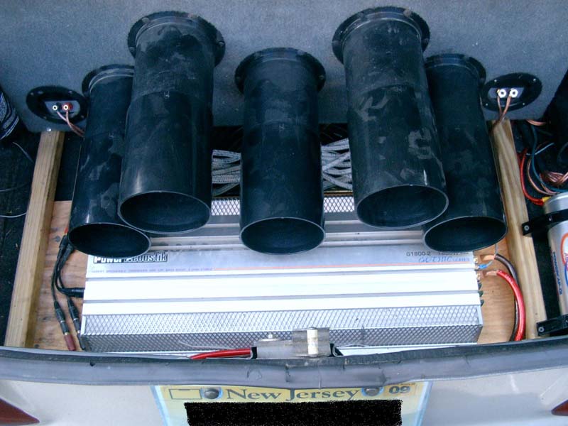 Car trunk with multiple subwoofers and an amplifier, New Jersey license plate visible