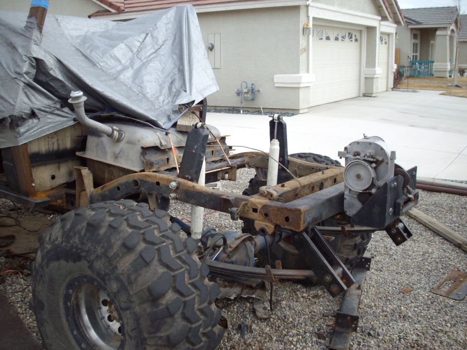 1982 Toyota 4Runner frame with suspension, large tire, and tarp-covered body section
