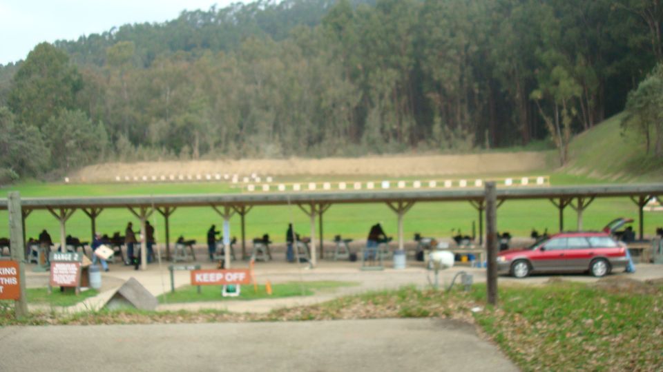 People shooting at a range with a red wagon parked nearby