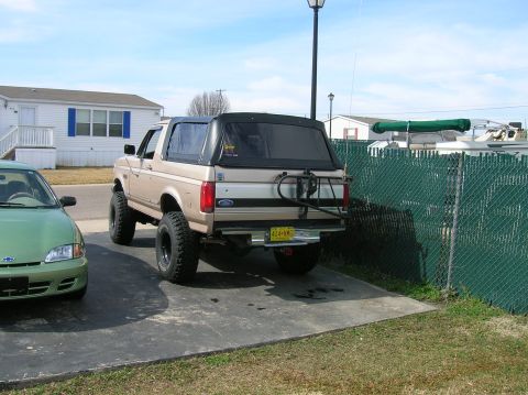 1996 Ford Bronco - Rear view of a 1996 Ford Bronco, showing its spare tire carrier and soft top.