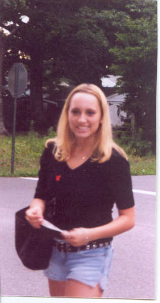 1986 Ford Taurus - A woman with blonde hair smiles while holding a piece of paper and a bag.