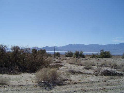 1989 Ford Bronco - A wide desert scene with sparse vegetation, mountains in the background, and a body of water visible on the horizon.
