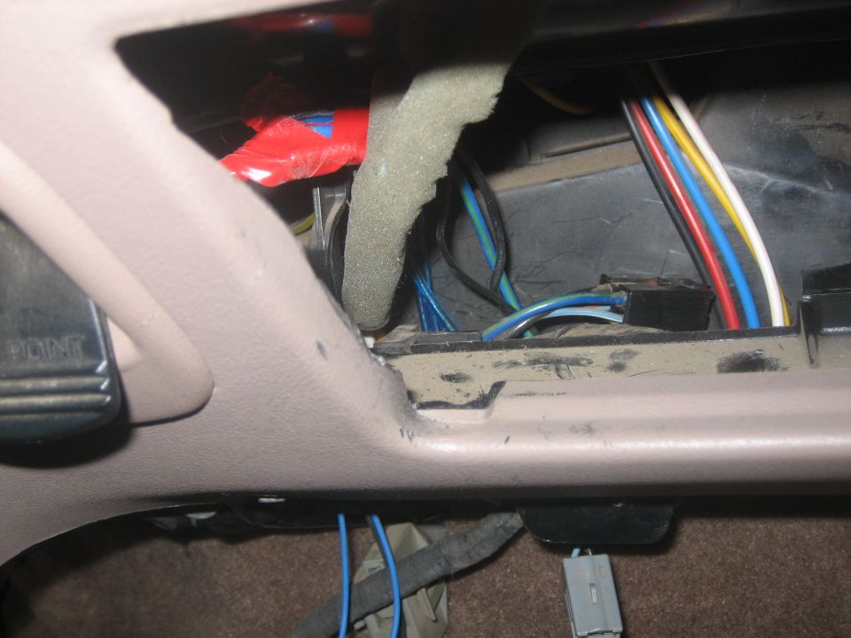 Empty tan dash radio cavity with loose colored wiring and connectors exposed