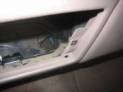 1995 Ford Bronco - Interior shot of a tan dash with a lower panel removed, exposing the cavity behind the glovebox area where a black wiring connector and blu…