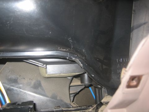 1995 Ford Bronco - Close-up of interior vehicle components, including ductwork, wiring, and a metal part, with some visible text on a plastic surface.