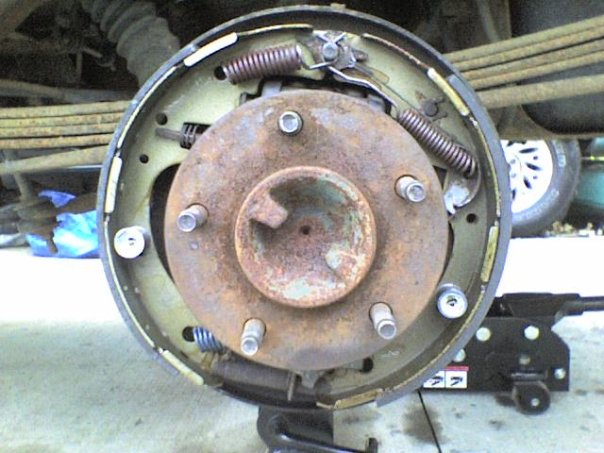 Close-up of a rusty drum brake assembly with springs and bolts