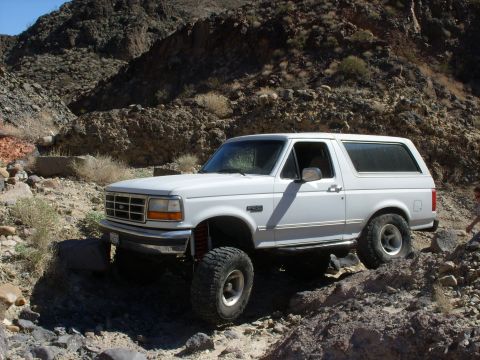 1993 Ford Bronco - White 1993 Ford Bronco tackles a challenging off-road path in a rocky canyon.