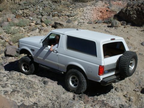 1993 Ford Bronco - A white 1993 Ford Bronco navigates a rocky, off-road path.